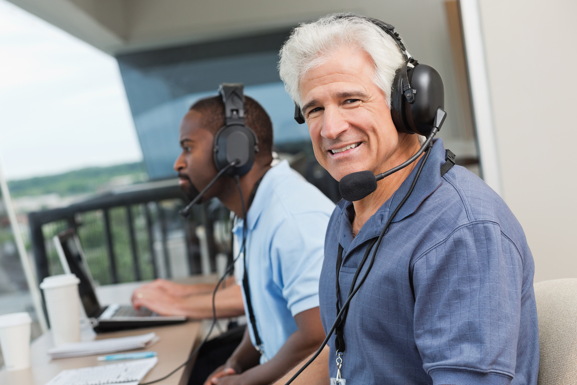 Senior sports commentator with other reporters in stadium press box